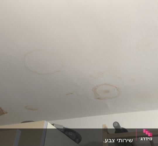 תקרה לבנה עם כתמי רטיבות ונזקי מים לפני צביעה ותיקון